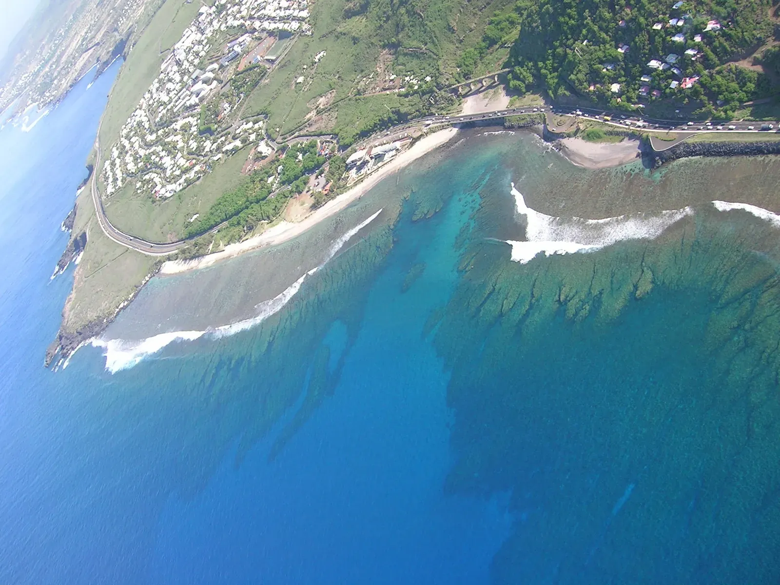 Vue aérienne d'une pointe rocheuse, du lagon et du village, depuis un parapente