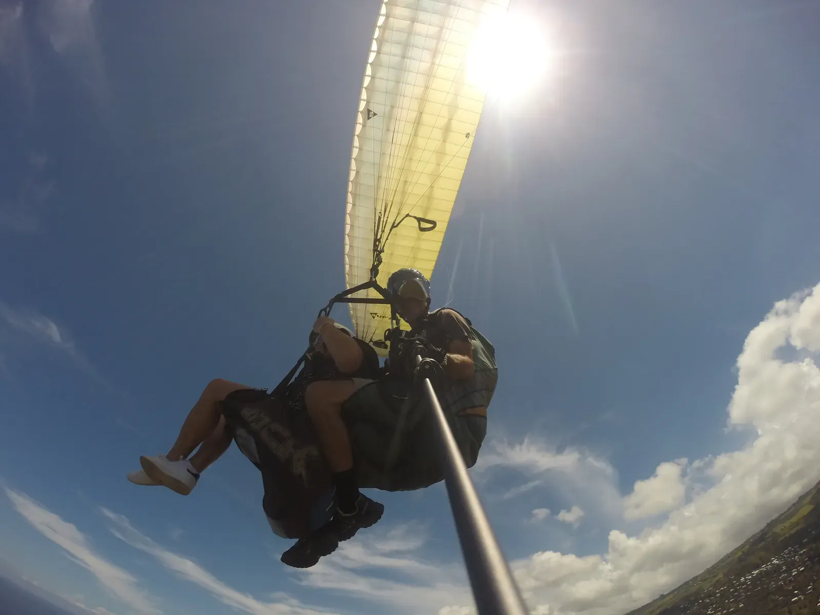 Voile de parapente à contre-jour, le biplace en silhouette dans le soleil