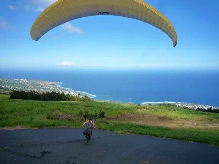 Pilote au décollage en solo face à l'océan, voile jaune gonflée au-dessus de la piste d'envol